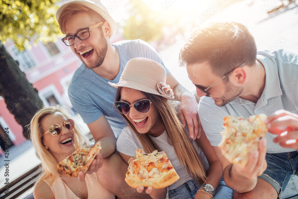 Wall mural friends having fun and eating pizza in the city