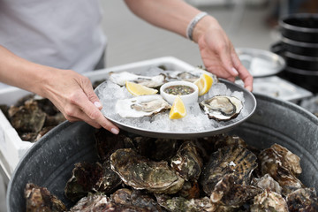 Close Up of Server with Tray of Fresh Shucked Oysters with Lemon Wedges Served as Appetizer