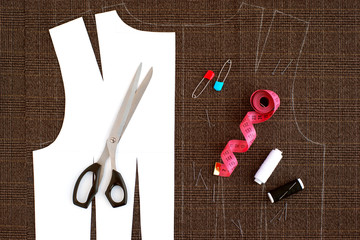 The process of sewing clothes from suit fabrics. Paper pattern, tailoring scissors, centimeter tape and fabric for sewing clothes. View from above.