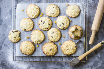 Homemade oatmeal cookies with chocolate chips on a gray kitchen table among accessories for baking. Top view, flat lay