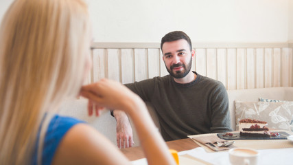 Obraz premium Young beard man and blonde girl have fun in a cafe