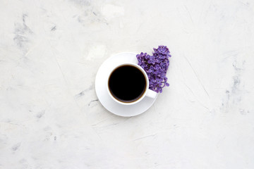 Obraz na płótnie Canvas White cup with a coffee and beautiful lilac flowers on a white background. Top view, flat, lay, copy space.