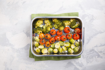 Oven baked vegetables with spices and herbs on baking tray. Grilled brussel sprouts, cherry tomatoes and broccoli. Top view, copy space.
