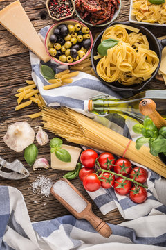 Italian food ingredients pasta olive oil parmesan cheese basil garlic mushrooms tomatoes olives on wooden table