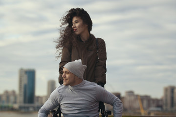 Portrait of a loving couple - beautiful woman with young disabled man on the hill overlooking the city