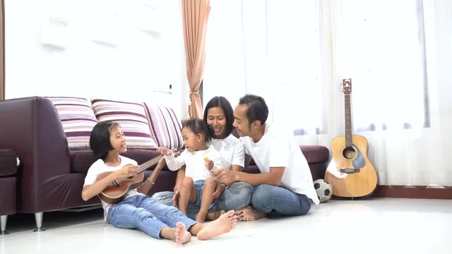 Happy Asian Family Play Ukulele Sing In Living Room At Home, Togetherness Relaxation Concept