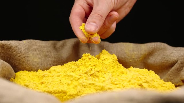 Human hand takes a pinch of a turmeric (curcuma) powder in a sac