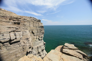 Cliff on spring time with the deep blue sea and sky with clouds
