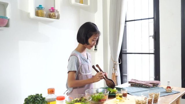 Asian little girl cooks in the kitchen at home