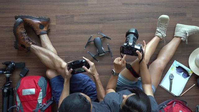 Traveler's Young couple backpack planning honeymoon vacation trip with holding camera with drone on wooden floor. Top view travel ideas concept