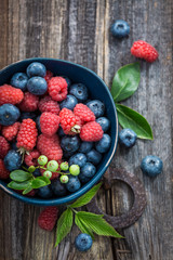 Fresh blueberries and raspberries in dark blue bowl