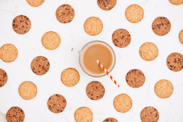 Cup of coffee among pattern of various shortbread and oat cookies with cereals and raisin on black wooden background. Top view, flat lay.
