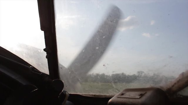 Propeller plane turning flying over green fields and houses view from cockpit