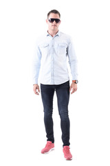 Fototapeta premium Man wearing light blue shirt, jeans and pink sneakers with sunglasses looking at camera. Full body isolated on white background. 