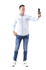 Serious adult elegant caucasian male fashion model taking picture with mobile phone. Full body isolated on white background. 