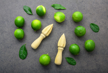 Fresh limes and wooden juicer on white background. Top view