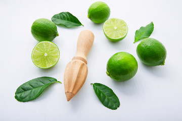 Fresh limes and wooden juicer on white background. Top view with copy space
