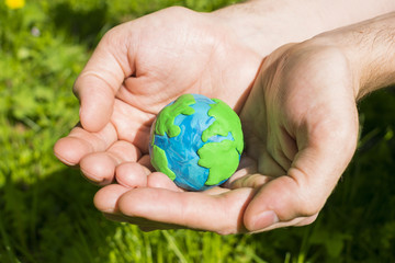 Plasticine Earth in man`s hand on the natural background.