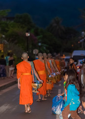 Obraz na płótnie Canvas LUANG PRABANG, LAOS - JANUARY 11, 2017: Feeding the monks. The ritual is called Tak Bat. Vertical. Copy space for text.