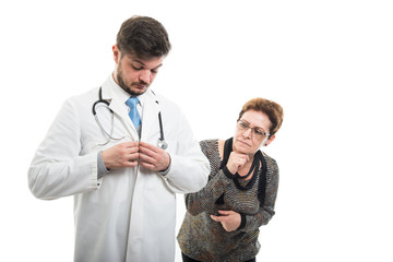 Senior patient looking at male doctor buttoning coat