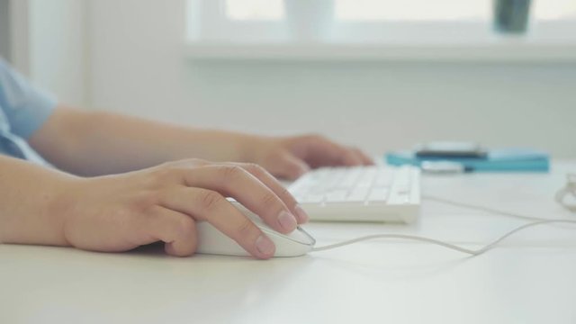 Male hand with computer mouse at office desk, man working on desktop pc