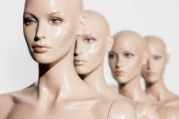 close-up view of naked bald mannequins in row on white, selective focus