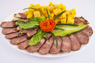 Festive decoration of a plate with homemade sausage, bacon, hard cheese and greens