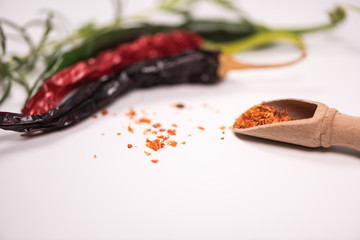 Chilli powder and fresh and dried peppers on table background
