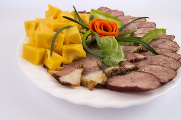 homemade sausage, cheese and bacon laid out in a white plate on a light background