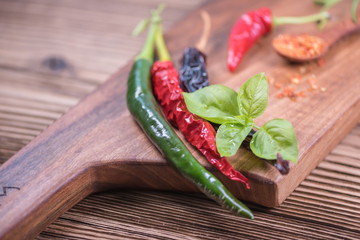 Chilli powder and fresh and dried peppers on table background