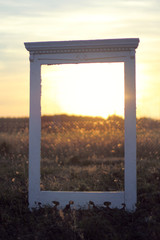 window in the sunset/ Retro frame of a portal standing in a field on a background of a blurred landscape