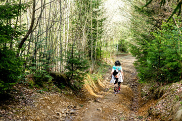 Obraz premium Woman walks on a forest road in a green forest.