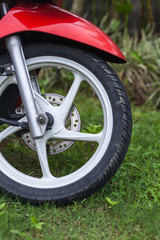 Fragment of front wheel with disc brakes of a red scooter
