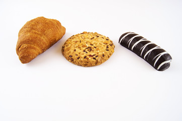 Croissant, biscuits with sesame seeds and nuts, cookies in chocolate on a light background