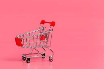 Shopping cart or supermarket trolley on pink background