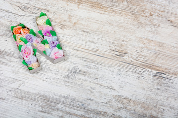 A letter N of artificial bright and beautiful flowers lying on a wooden textured background, flatlay, Copyspace