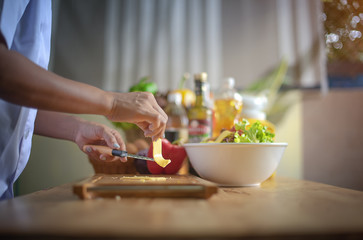 cheese in hand of chef slice over breadboard trencher for made burger and salad, being prepare breakfast in daily meal in kitchen