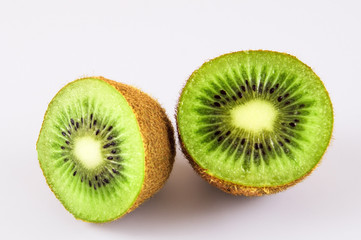 Two halves of green kiwi on a light background