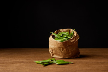 paper bag of pea pods on wooden tabletop