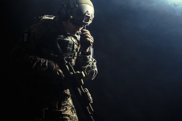 Special forces soldier with rifle on dark background