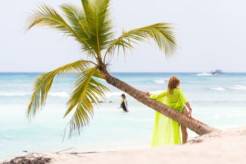 SAONA, DOMINICAN REPUBLIC - MAY 25, 2017: A woman near a palm tree on a sandy beach. Copy space for text.