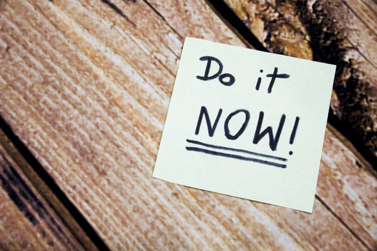 Do it now conceptual handwritten message on the white paper. Business concept handwritten messages. Motivational and positive handwritten messages with wooden background.