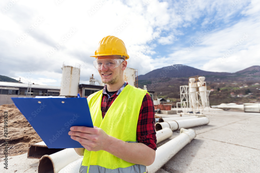 Wall mural Male construction worker looking at clipboard