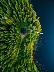 Aerial view of wooden cottage in green forest by the blue lake in rural summer Finland
