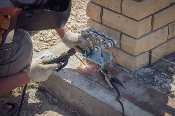 The worker installs rollers on the sliding gate