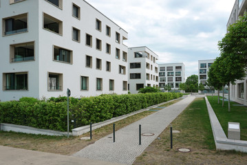 Row of white residential buildings with balconies and rectangular windows in a modern district.