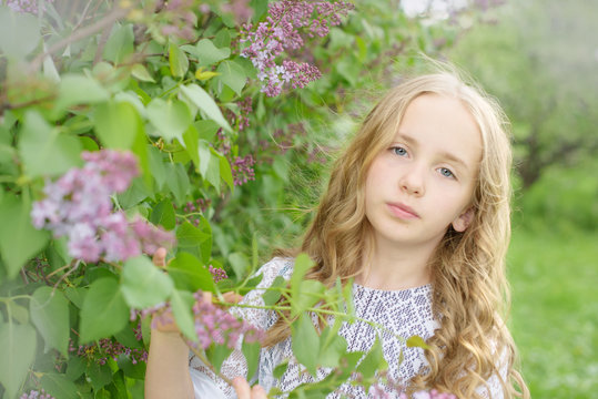 blonde hair girl in a blooming lilac garden