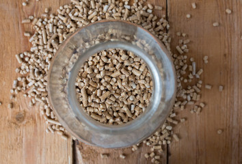 Wooden pet bedding in the glass jar standing on the plank. Wood pellets background.