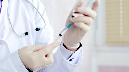 Medical doctor with syringe in hands is preparing for injection