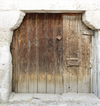 Ancient trapezoidal antique wooden doors with a wooden lock in the middle